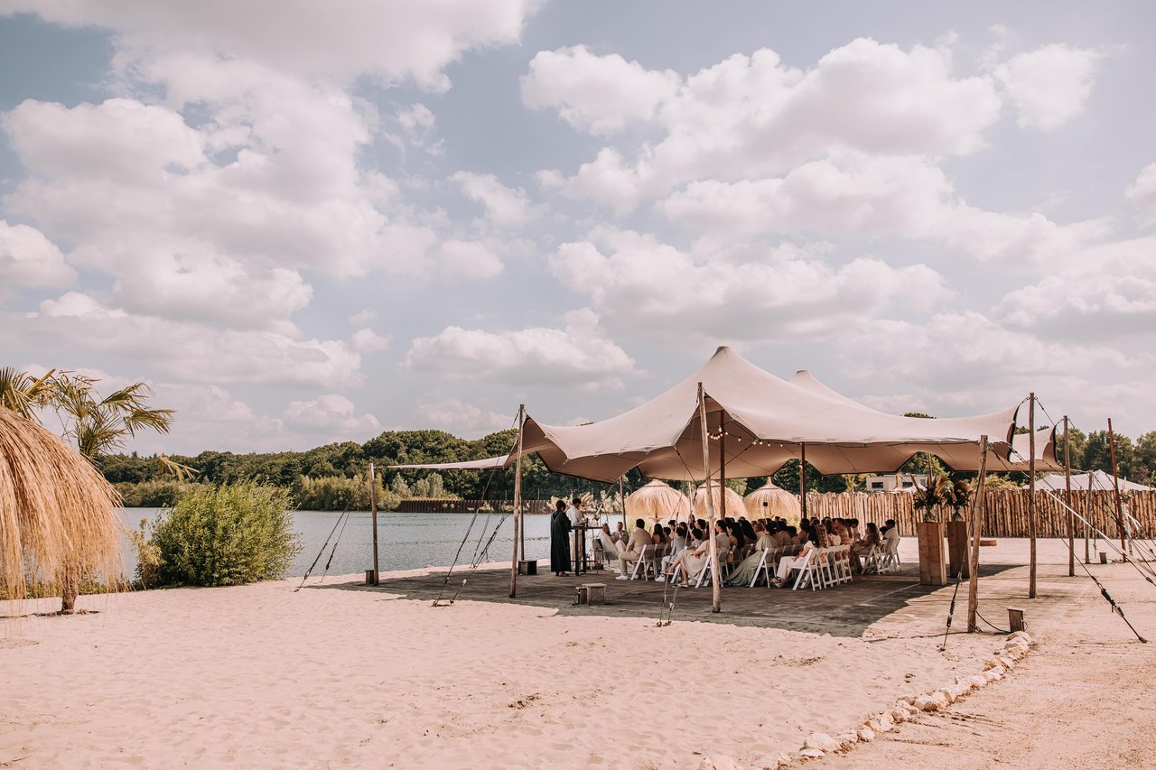 Bruiloft aan het water onder een sfeervolle stretchtent